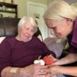 A personal care aide interacts with a client that is holding small knitted pumpkins.