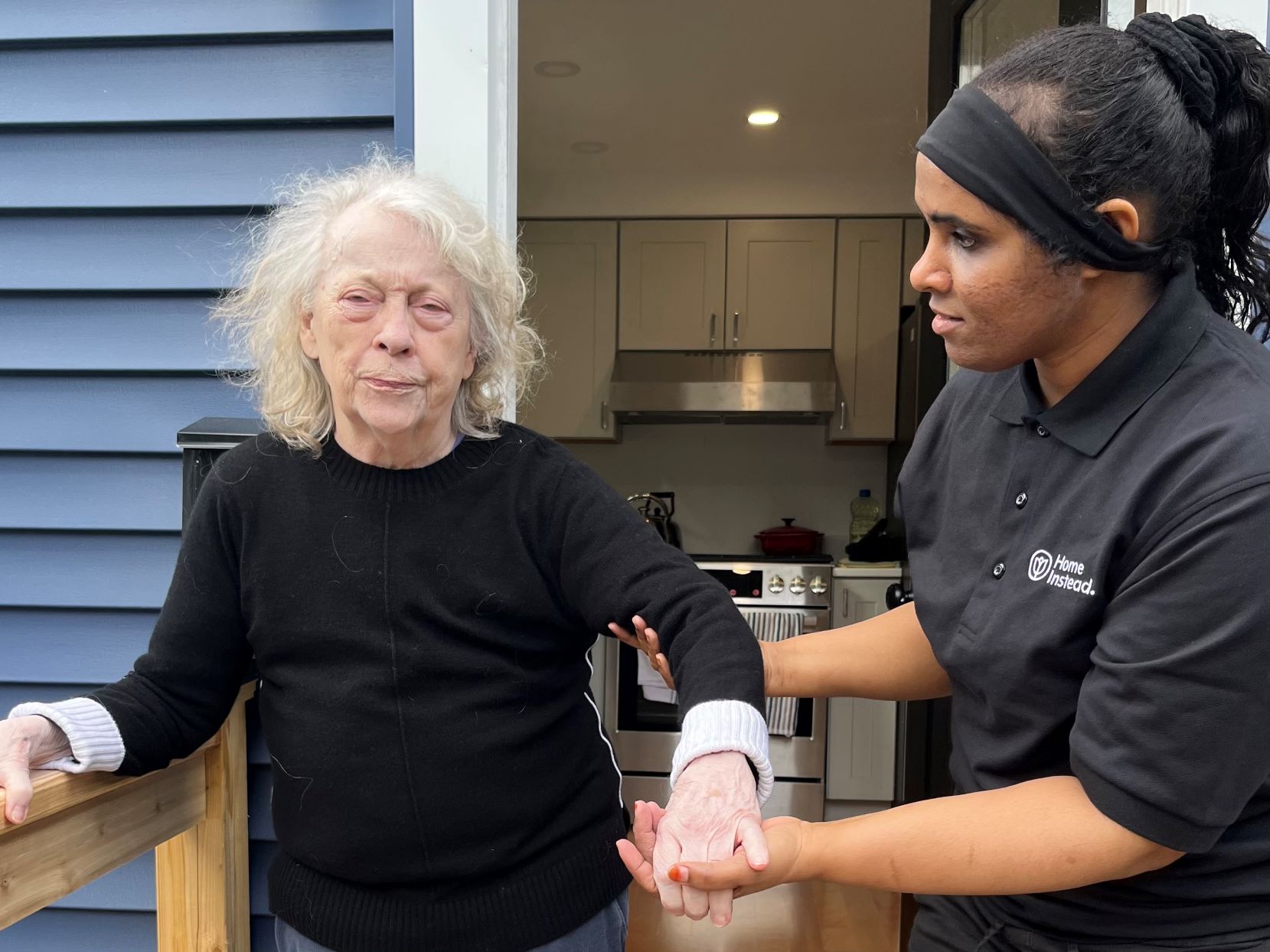 A woman receives assistance walking from her personal care aide.