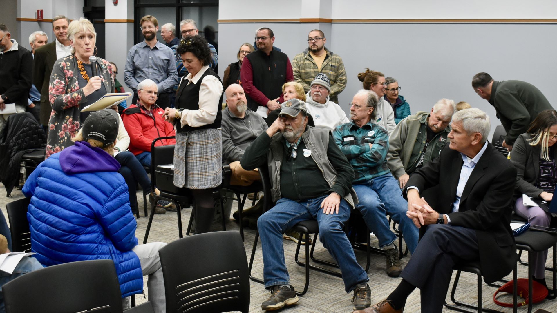 A speaker stands among a crowd of attendees at a hearing in Bucksport.