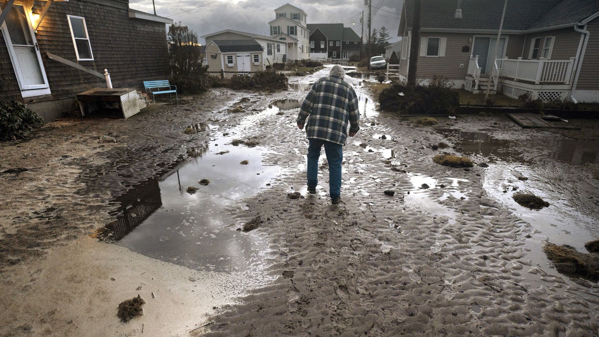 A man walks through a flooded residential street.
