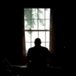 a silhouette image of a nursing home resident looking out a window.