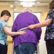 Two nurses help a patient walk with a walker.