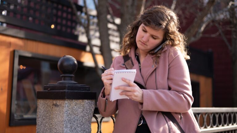 Maine Monitor reporter Rose Lundy jots down notes while on a phone call.