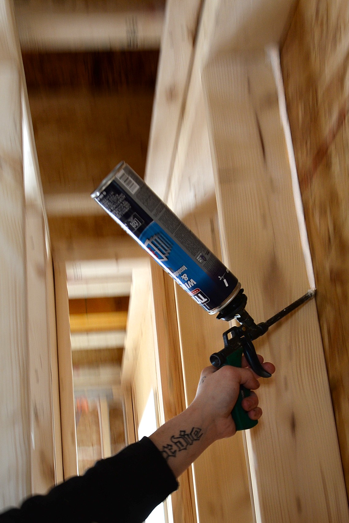 A worker uses expanding foam to plug holes in the building.