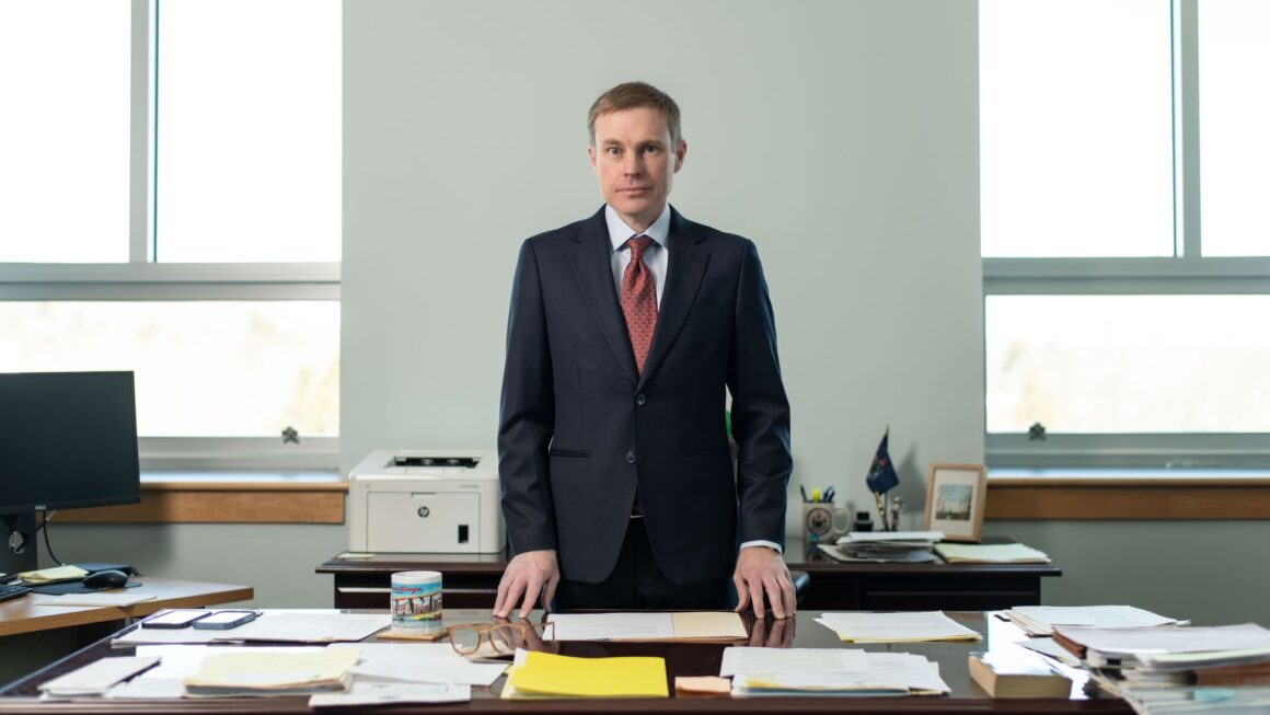 Aaron Frey poses for a photo while standing behind his desk.
