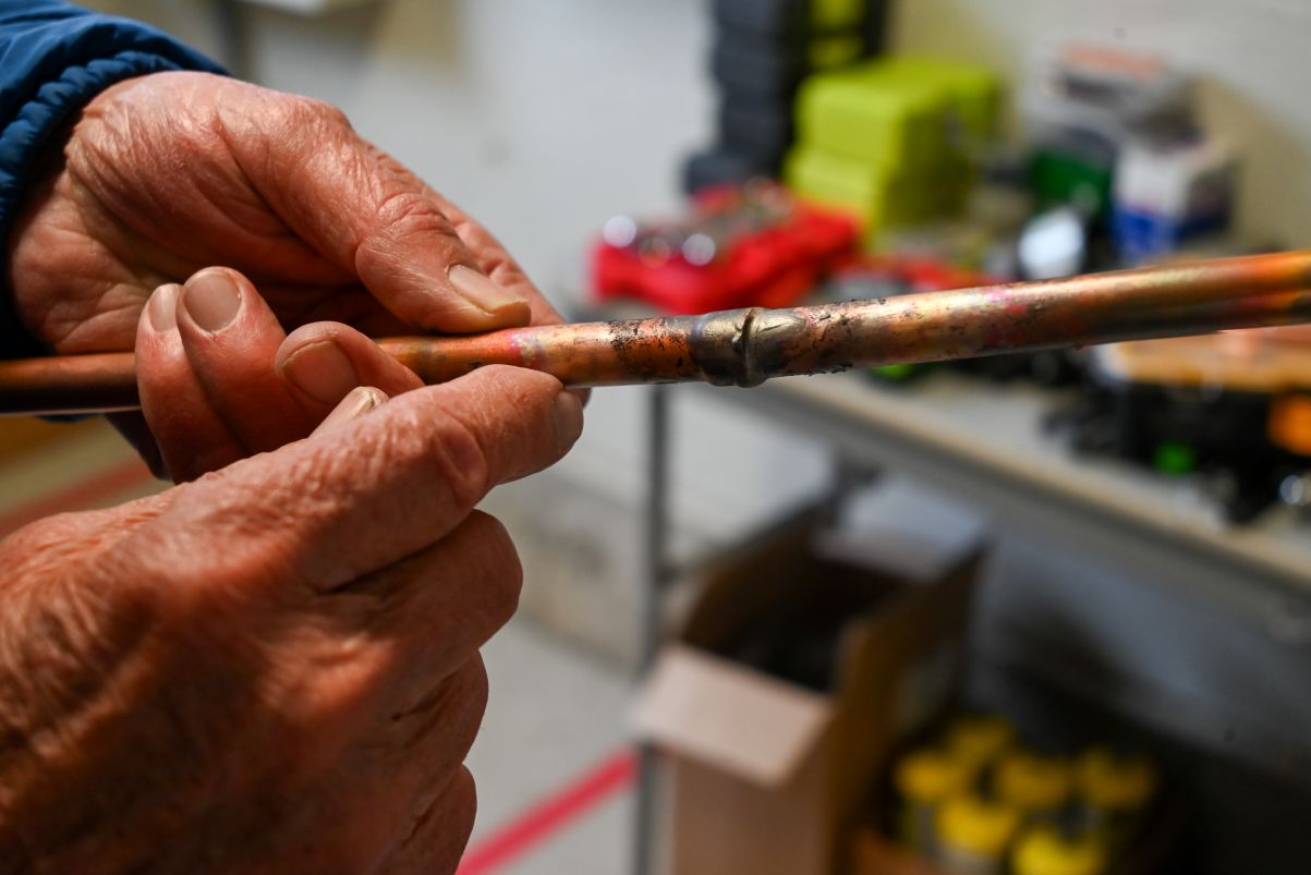 hands holding copper tubing.