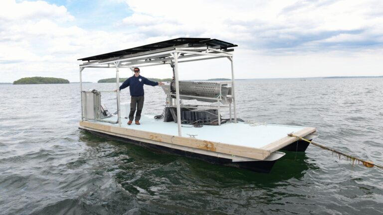 a man stands on an oyster processing barge.