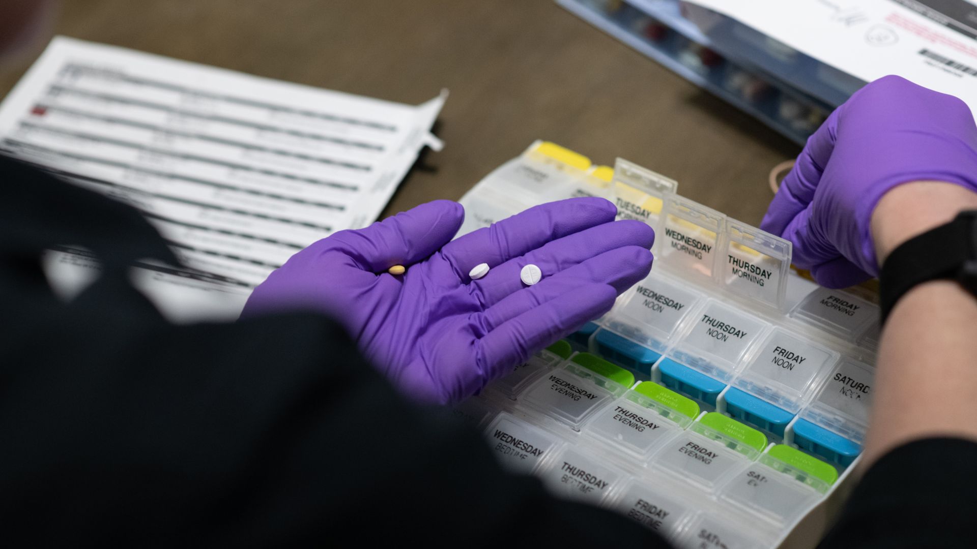 a community paramedic sorts pills into a container.