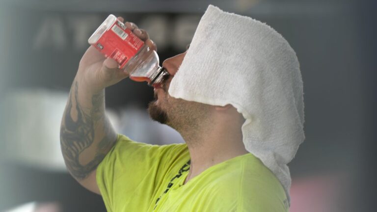 a man wearing a towel on his head drinks a bottle of juice.