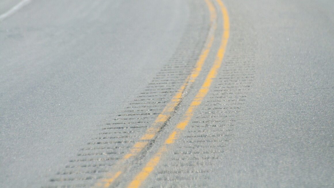 rumble strips line the middle of a road that is divided by two yellow lines.