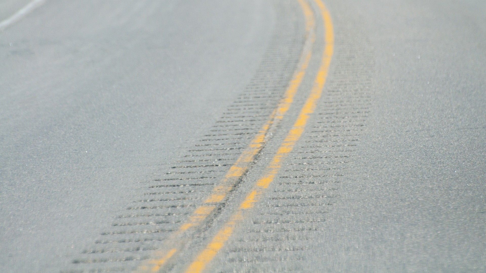rumble strips line the middle of a road that is divided by two yellow lines.