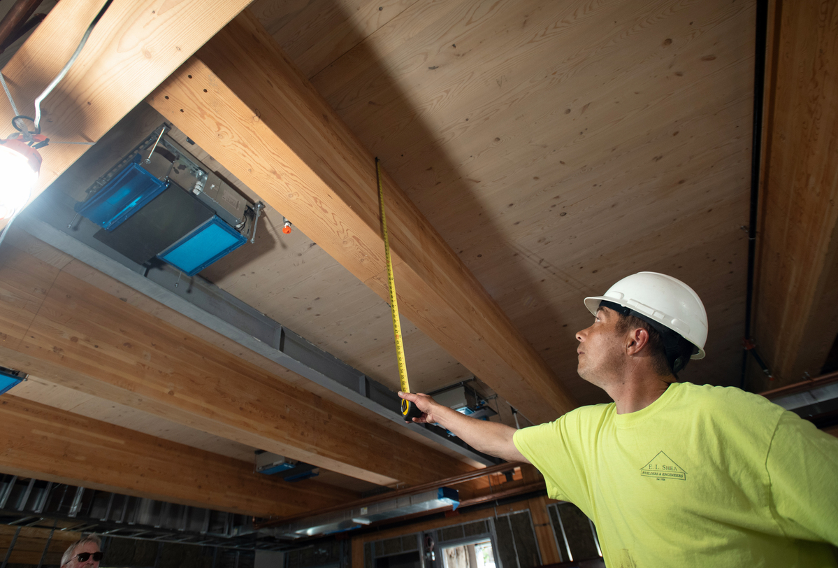 A measurement of a beam is taken by tape measure.