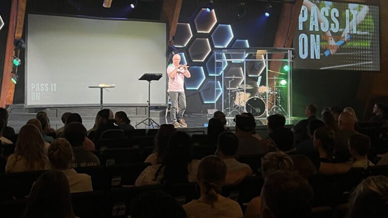 A man standing on stage preaching to his congregation.