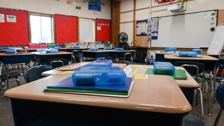 school supplies on top of desks inside a classroom.