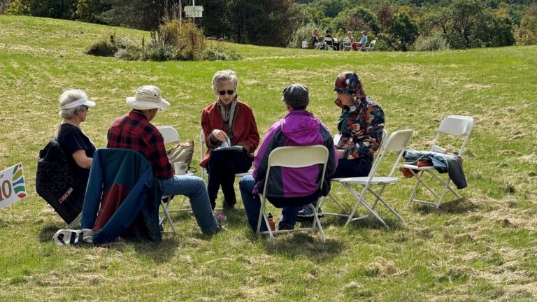 A small group sits in an open grass field.