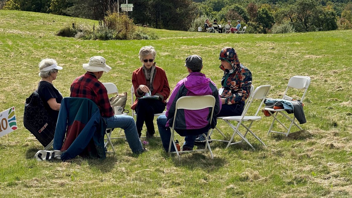 A small group sits in an open grass field.