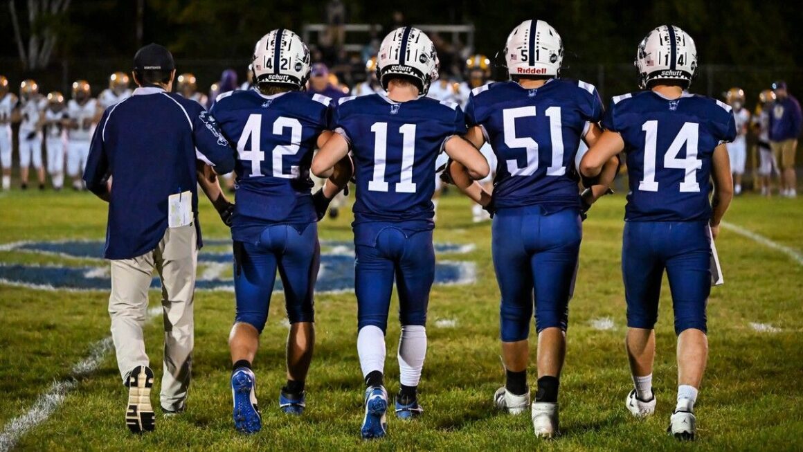 a small group of football players head to the middle of the field.