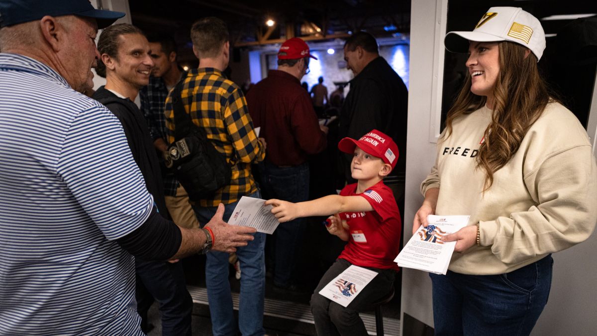 a young boy hands out programs alongside his mother.
