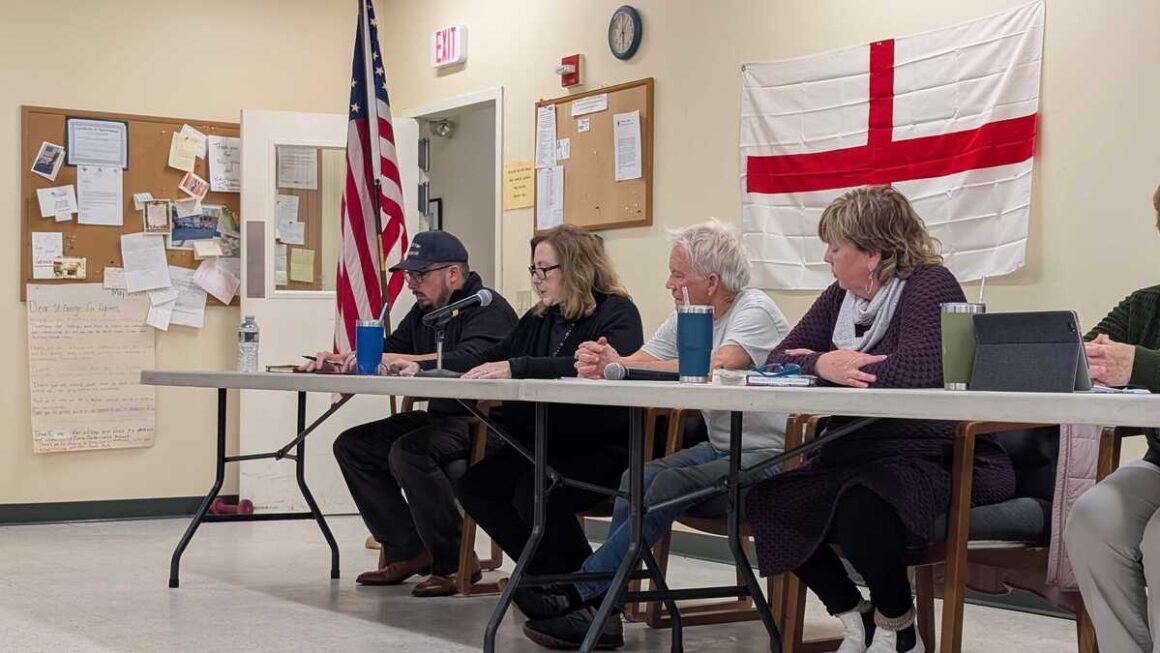 members of the select board sit during a meeting.