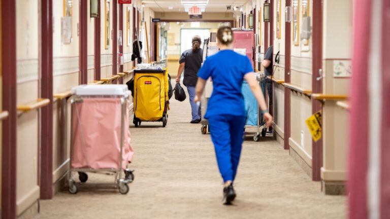 staff members walk down a nursing home hallway.