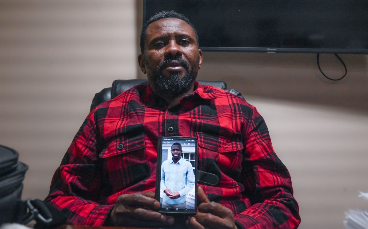 Carlos Nzolameso holds a cellphone showing an image of Evaristo Kalonji.