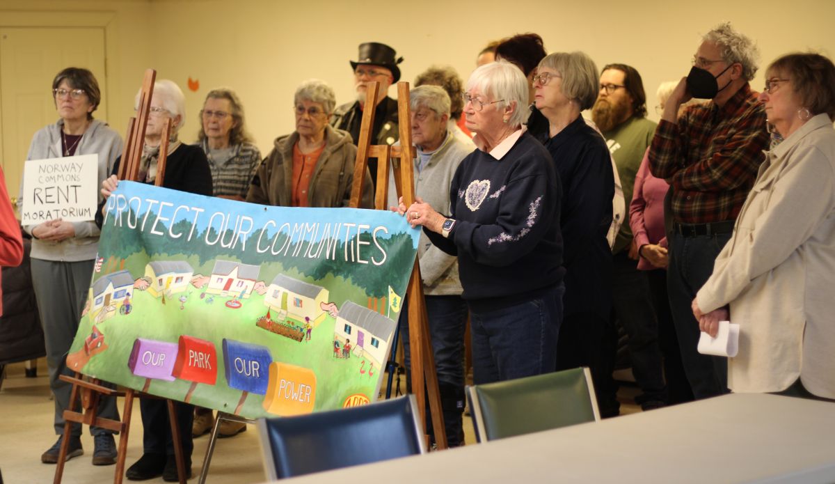 Residents of Norway Commons stand behind a banner 