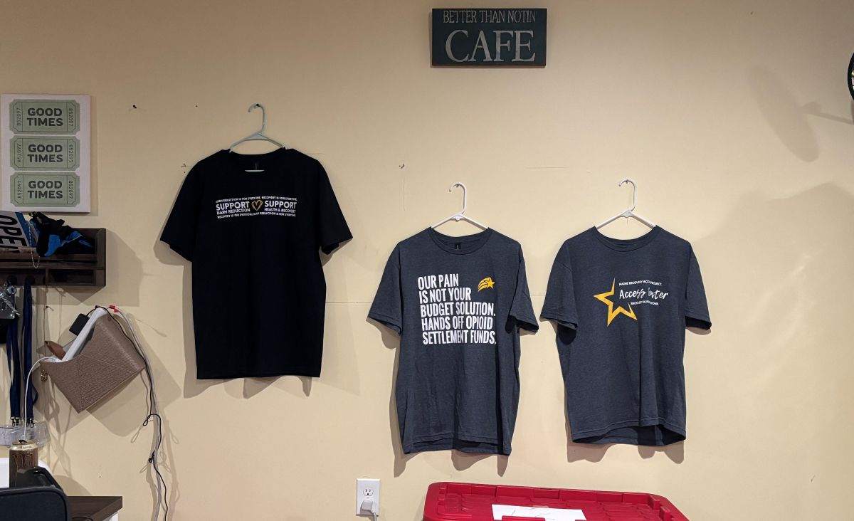 three t-shirt designs on display on a wall.