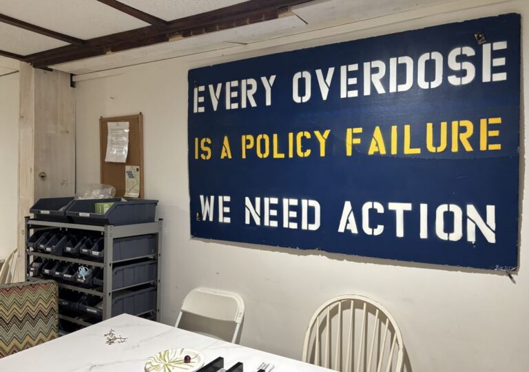A sign on a wall reads “Every overdose is a policy failure. We need action.”