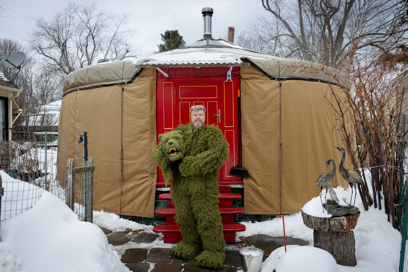 Paul Ridlon stands in front of a yurt wearing a Moss Bear suit.