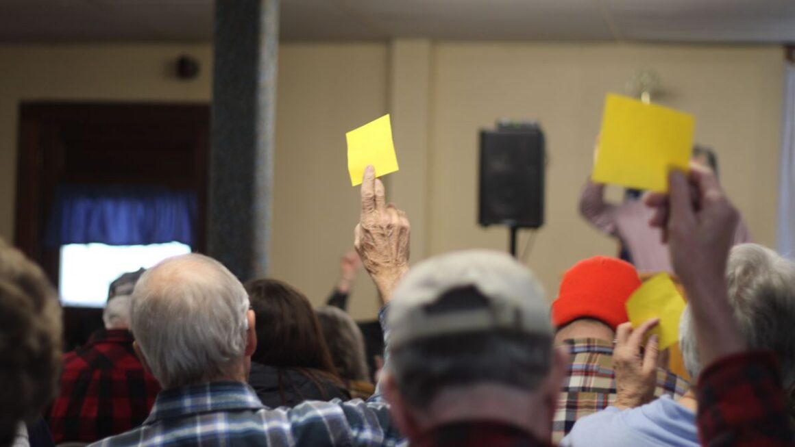 residents raise yellow sticky notes to cast their vote.