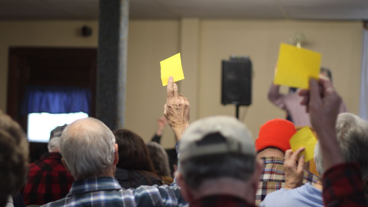 residents raise yellow sticky notes to cast their vote.