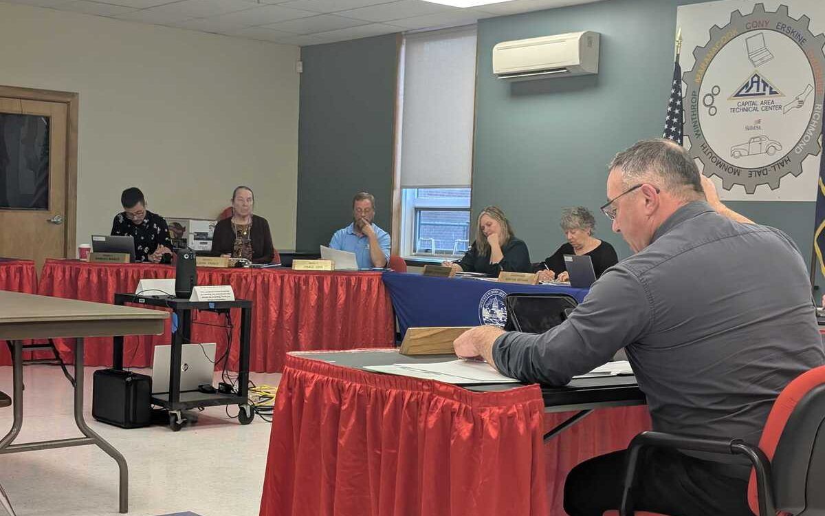 people sitting around tables during the school board meeting.