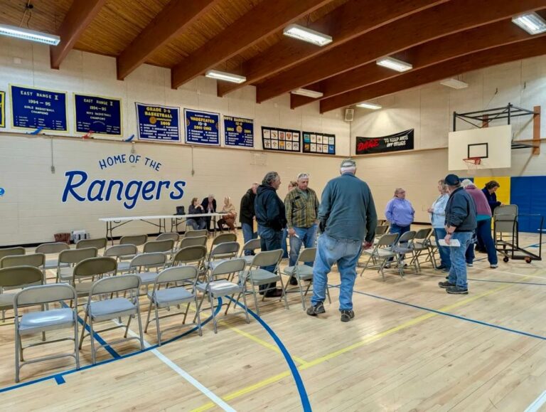 People gather amid chairs in a gymnasium
