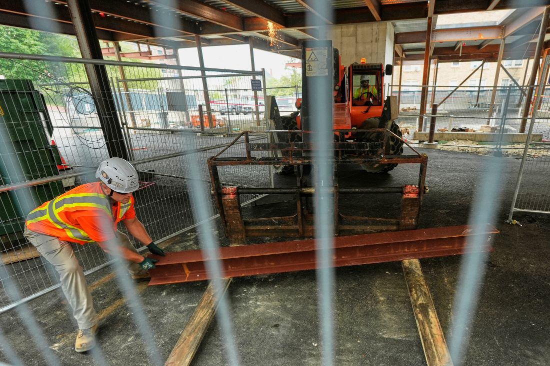 A worker moves a steel i-beam at the site of a construction of a housing project.