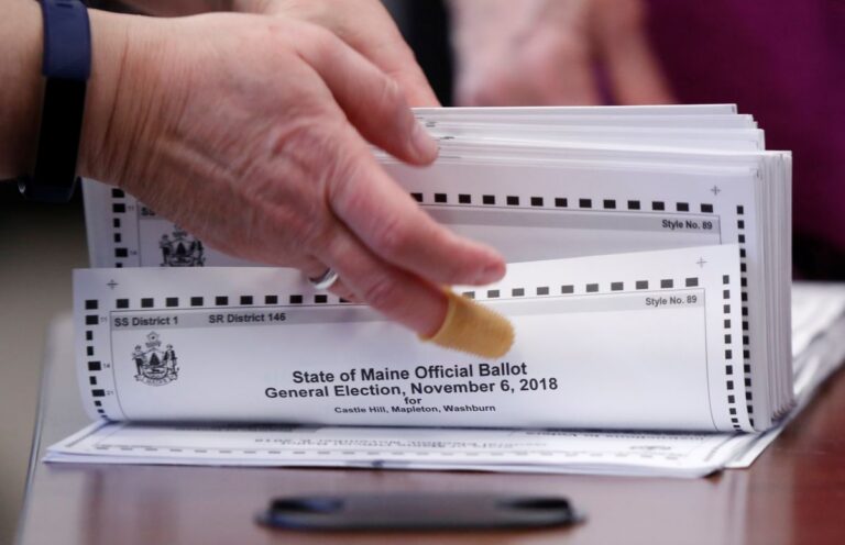 an election worker prepares a stack of ballots for tabulation.