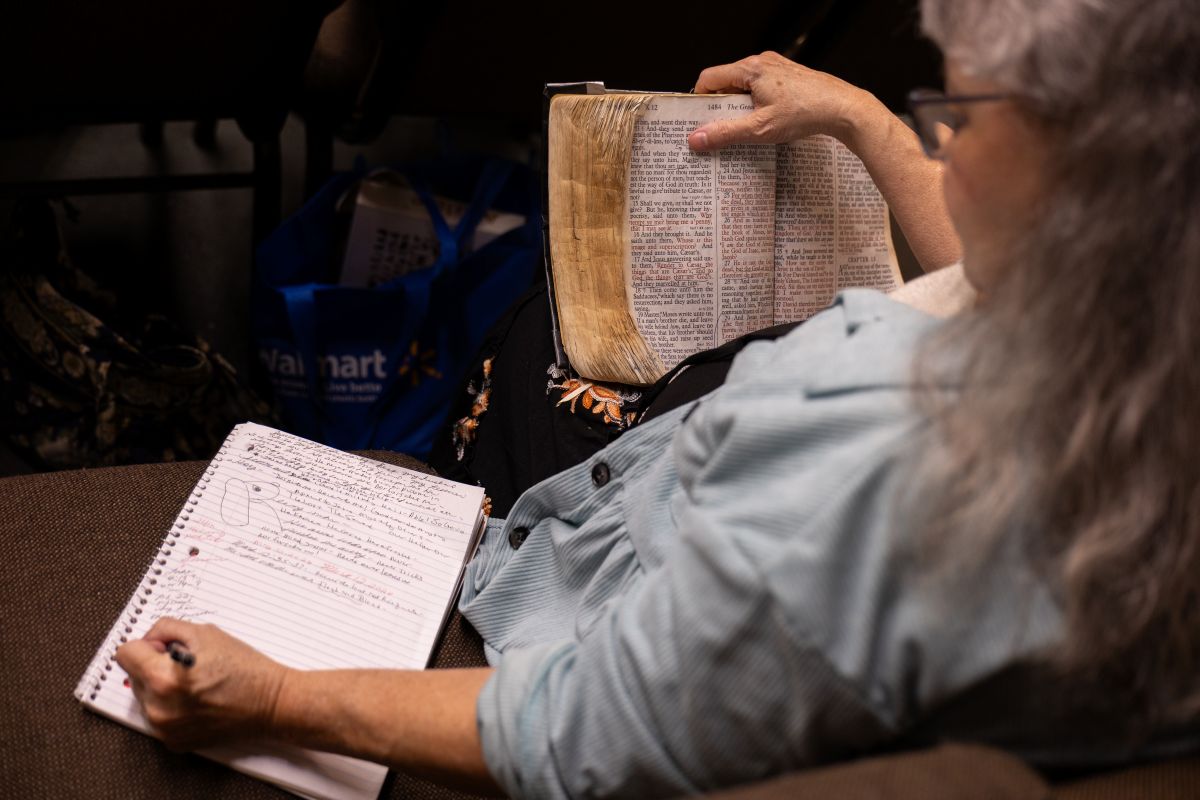 A woman taking notes while holding a bible.