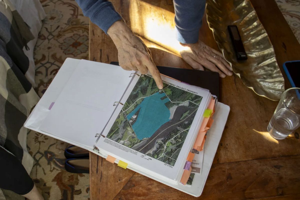 a hand points to a map that is within a binder.