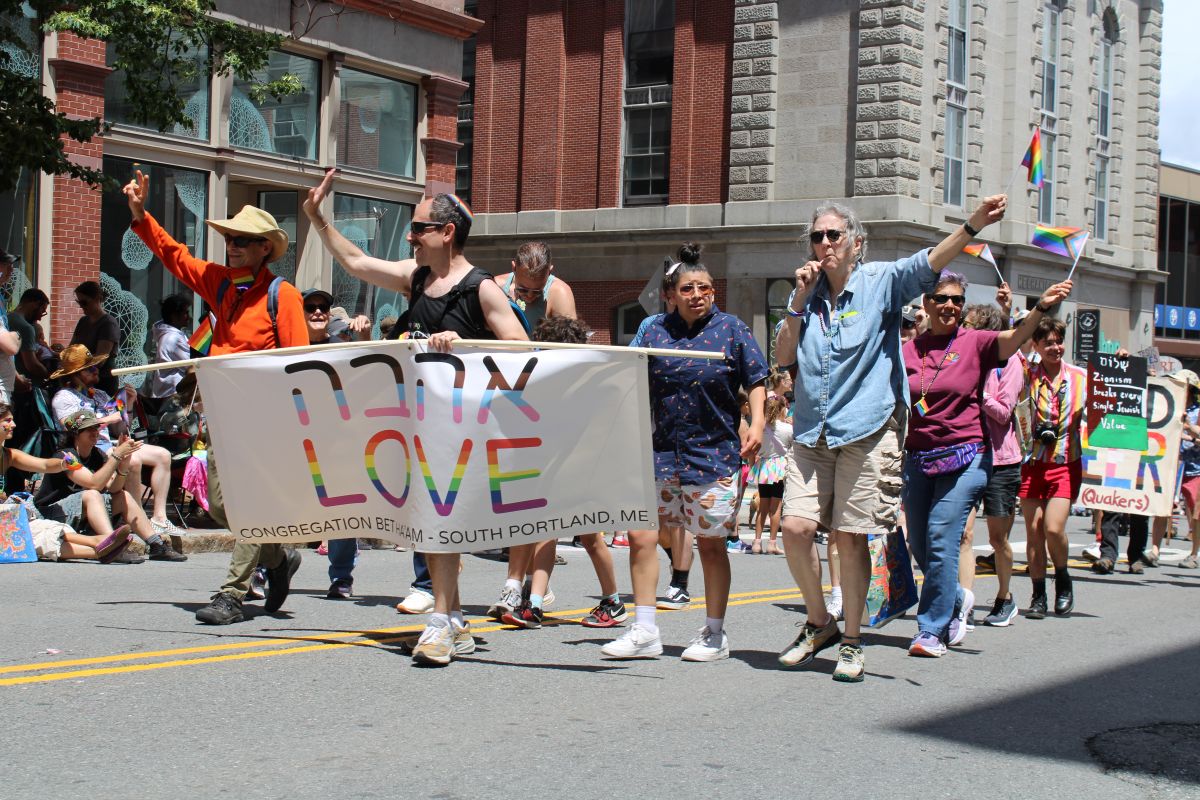people walking during a pride parade with a banner that reads love