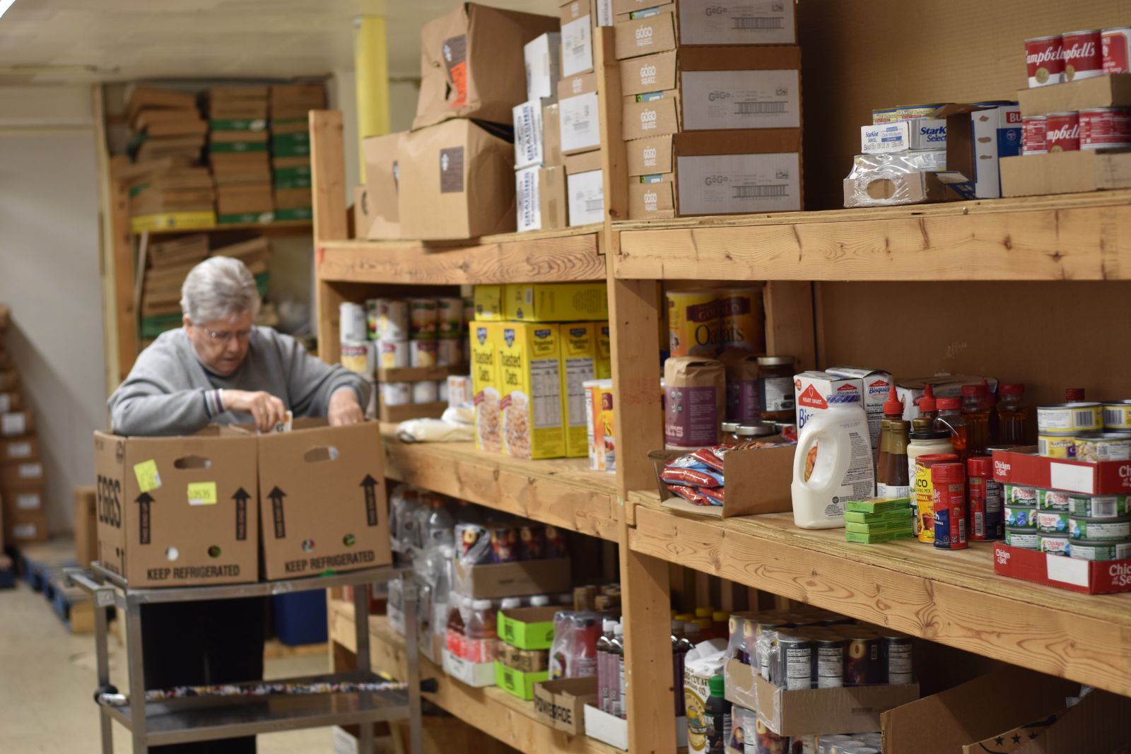 a food pantry volunteer loads items into a box from a shelf