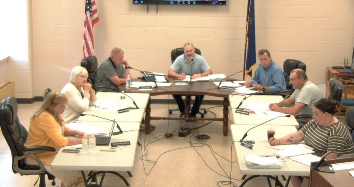 Members of the council sit around tables during a meeting.