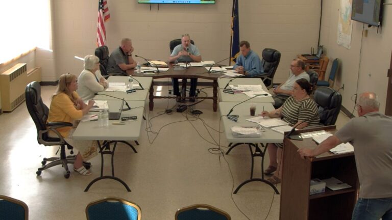 Members of the council sit around tables during a meeting.