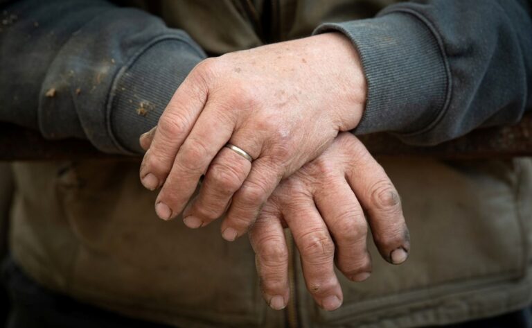 a man's left hand rests on top of his right hand.