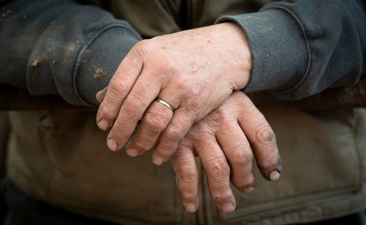 a man's left hand rests on top of his right hand.