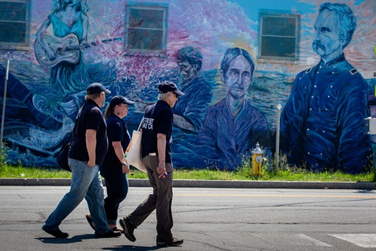 a trio of volunteers walking down a street.