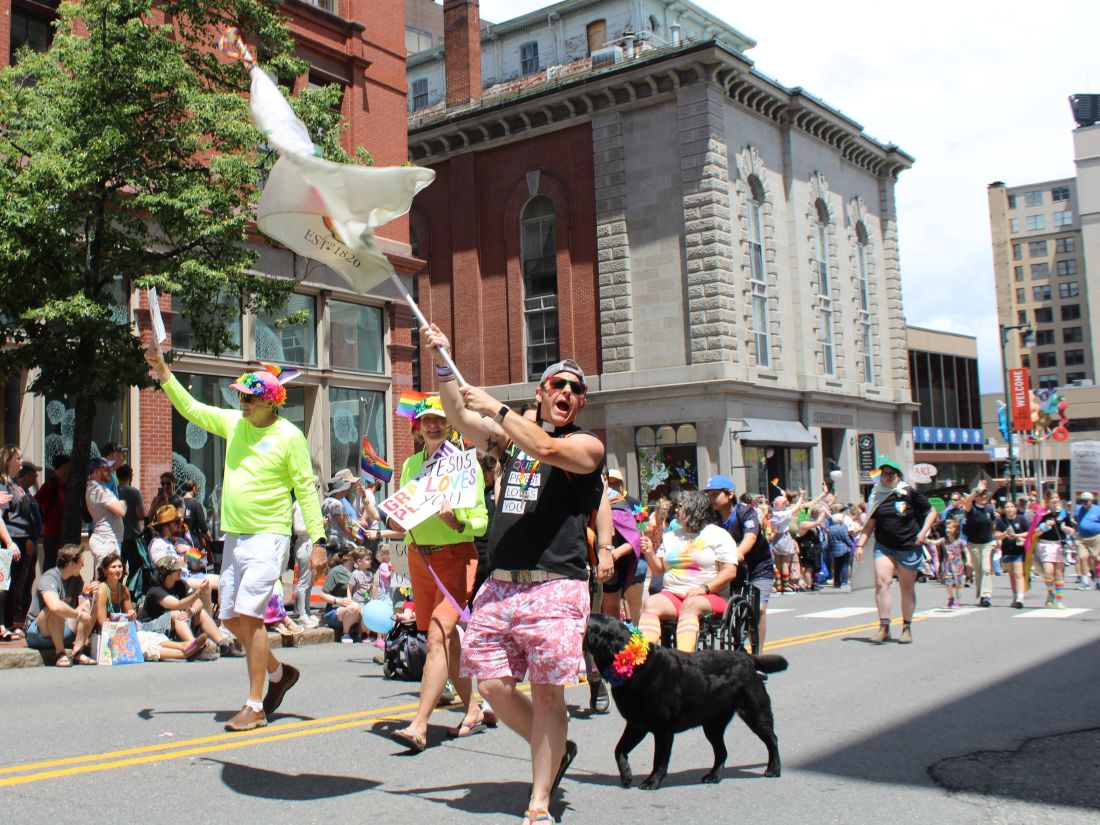 Rev. Lauren Kay waves the Episcopal Diocese of Maine flag during the Portland Pride parade. 