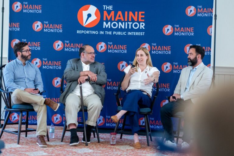 Panelists sit in front of a blue Maine Monitor sign
