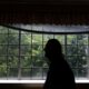 a silhouetted man stands in front of a window.