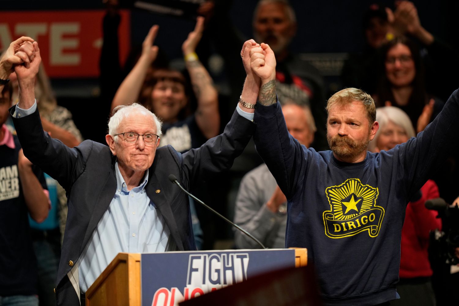 Bernie Sanders and Graham Platner pose with their arms jointly raised during a campaign event.