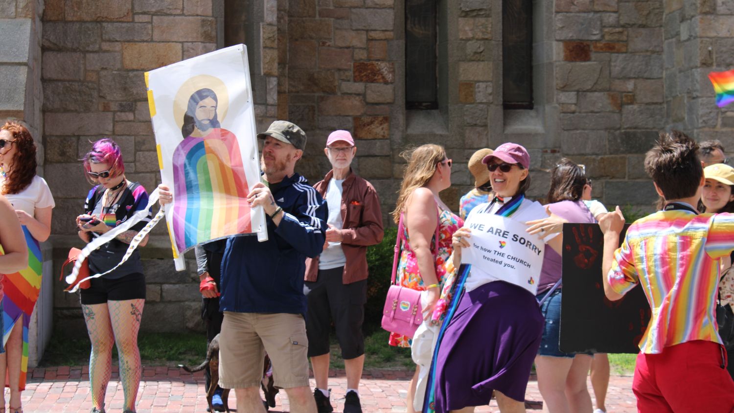 Rev. Reba Delzell holds a sign that reads “We are sorry for how the church treated you”