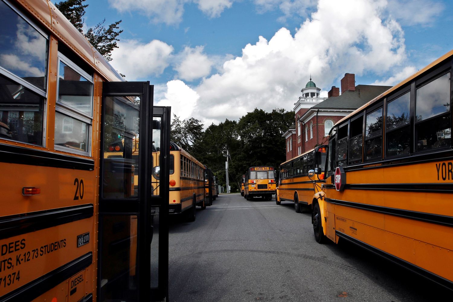 buses lined up with their doors open outside a school.
